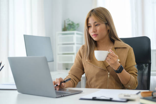 istock Happy young businesswoman drinking coffee and working at bright office. 1490205432
