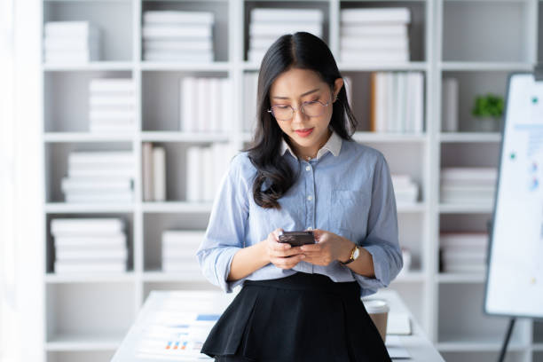 istock Happy Asian businesswoman using smartphone while working in hte office room. 1490207412