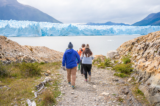 El Calafate Santa Cruz Argentina - January 13, 2023: A small group of people are walking through an area of many stones to reach the Perito Moreno glacier.
