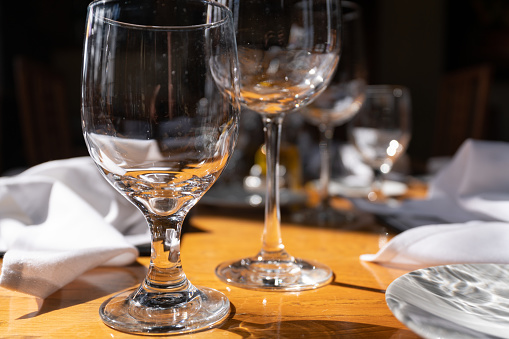 Empty wine glasses, forks and knives close up view on wooden table in restaurant