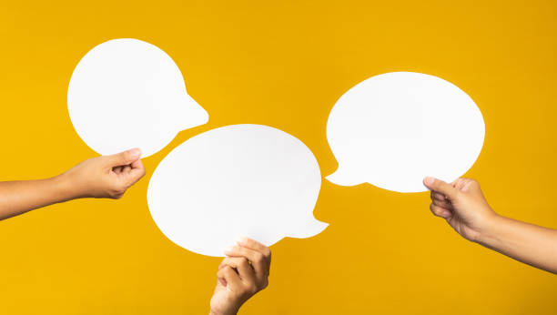 istock Hand holding of an empty white speech bubble against a yellow background 1490232464