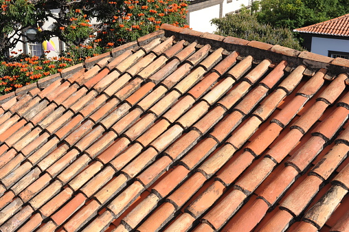 Red and orange roof tiles texture pattern on roof of an old historical building in Portugal