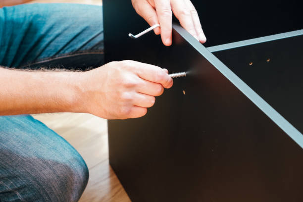 istock Assembling furniture. Furniture Assembly Worker Assembles Shelf. Service man assembling furniture for customer, Delivery service furniture store and assembling for buyer. 1490246989