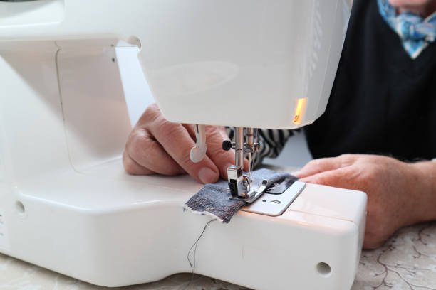 istock An old male tailor sews on an electric sewing machine. Close-up on hands 1490247417
