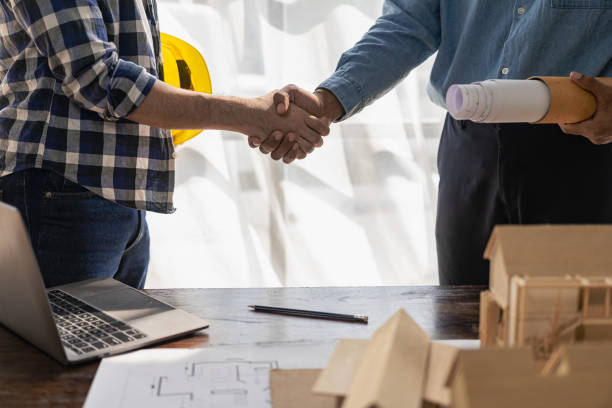 istock Construction workers holding helmets and vests are shaking hands. real estate concept Architect shaking hands with engineer or builder planning and successful meetings 1490258034