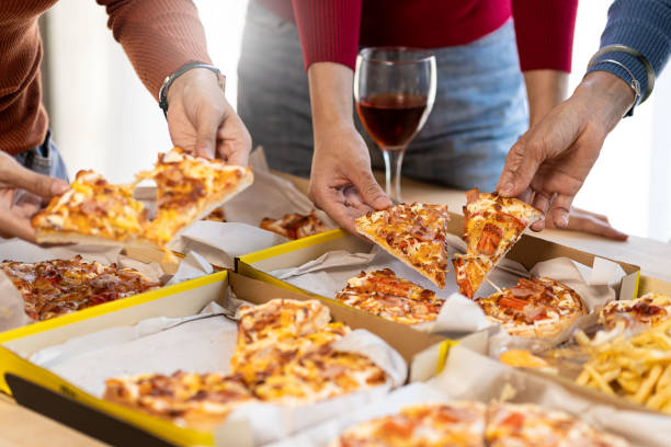 istock Colleagues having lunch at pizza party and eating assorted pizzas and drinking red wine on rustic wooden table celebrating fast food lunch 1490258090