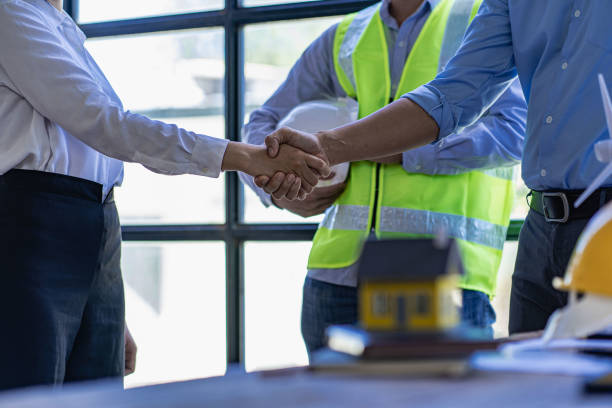 istock Construction workers holding helmets and vests are shaking hands. real estate concept Architect shaking hands with engineer or builder planning and successful meetings 1490258179