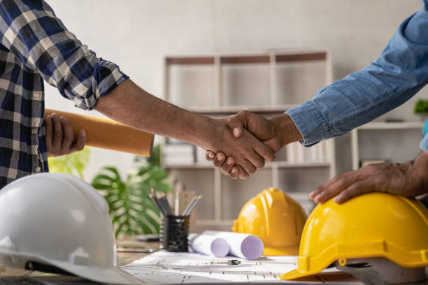 istock Construction workers holding helmets and vests are shaking hands. real estate concept Architect shaking hands with engineer or builder planning and successful meetings 1490258239