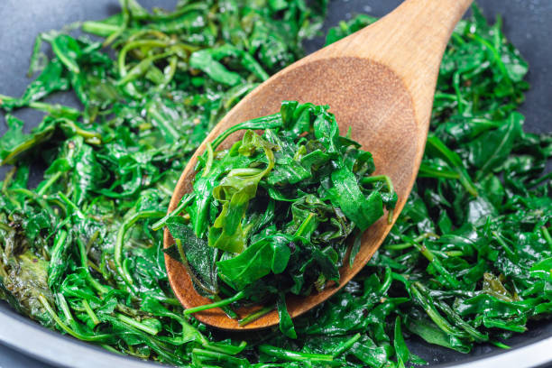 istock Preparing a side dish to steak, Wilted arugula or rocket salad in frying pan, horizontal, closeup 1490260076