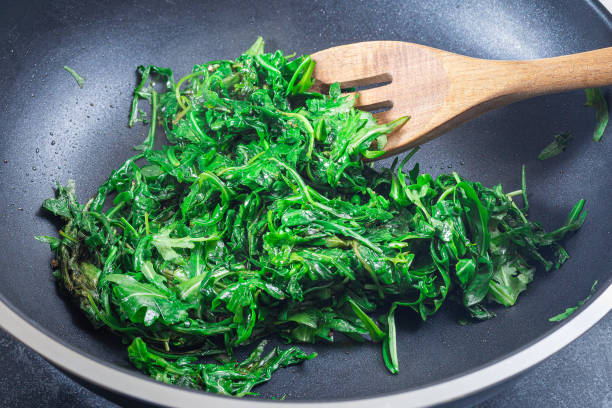istock Wilted arugula or rocket salad, preparing a side dish to steak, in frying pan, horizontal 1490261354