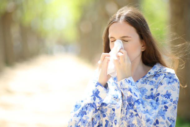 istock Allergic woman blowing on tissue in a park 1490264101