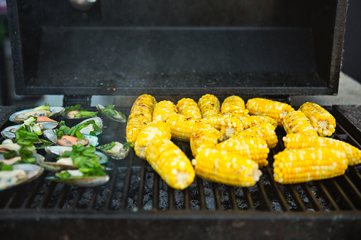 Cooking green mussels and corn on cob on char bbq