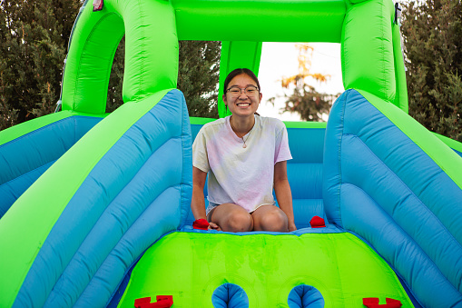 Happy asian girl sitting on bouncy house water slide