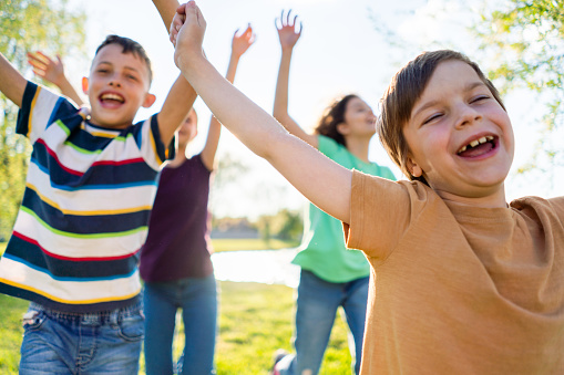 Group of happy children whit their arms outstretched running in the nature