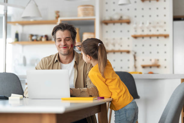 istock Smiling man working online while his daughter using a red chopstick on him. 1490267689