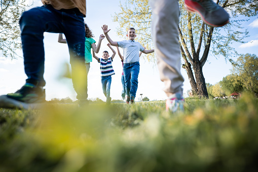 Low angle view of group of happy children running in nature during sunny day