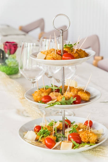 istock Fried breaded prawns with rocket salad on a porcelain cake stand on a white, elegantly set table, vertical 1490270680