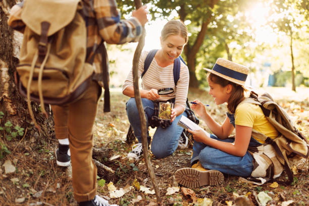 istock Happy mother and two   children in   with backpacks examining environment through magnifying glass in forest 1490270844
