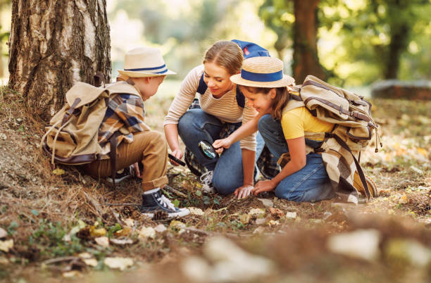 istock Happy mother and two   children in   with backpacks examining environment through magnifying glass in forest 1490271466