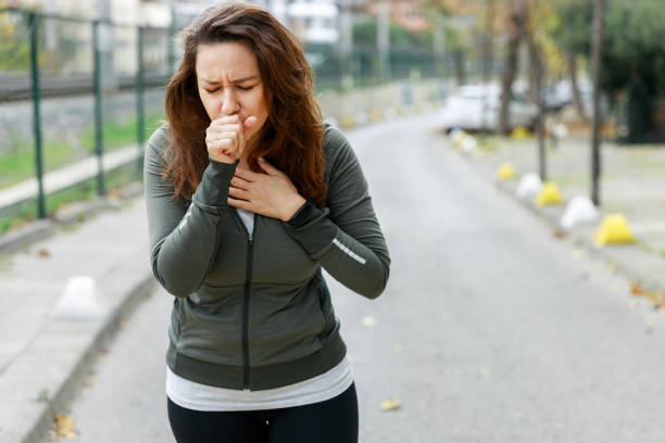 Young sporty woman coughing while walking on the street stock photo