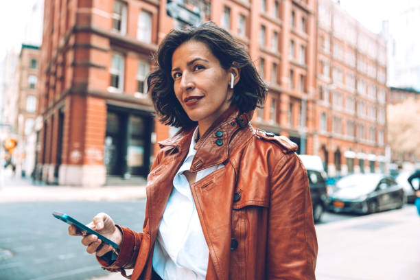 mujer de moda caminando a la oficina escuchando mensajes de voz en auriculares - city street audio fotografías e imágenes de stock