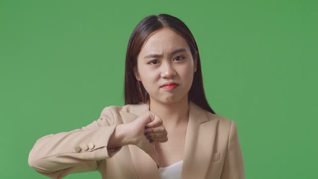 Close Up Of Asian Business Woman Showing Thumbs Down Gesture While Standing In The Green Screen Studio