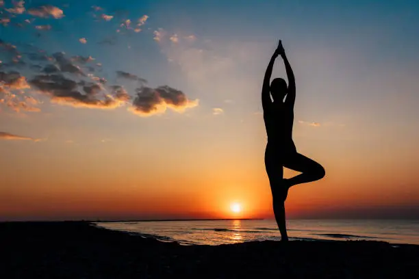 A girl gracefully strikes a yoga asana on the beach, connecting with the serene beauty of the surroundings while finding inner peace and balance.
