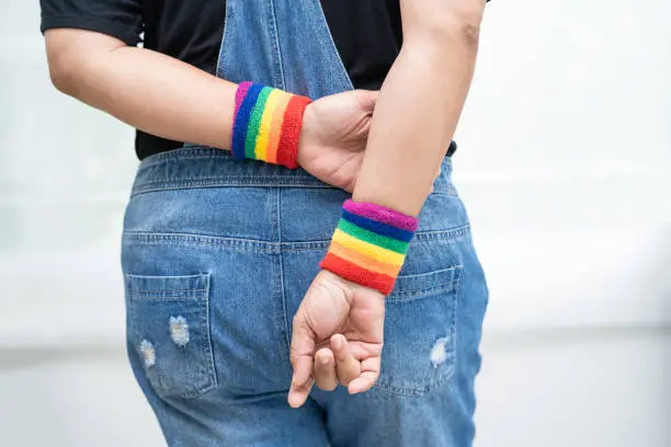 Asian lady wearing rainbow flag wristbands, symbol of LGBT pride month celebrate annual in June social of gay, lesbian, bisexual, transgender, human rights.