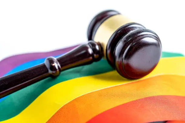 A gavel, symbolizing the authority of judges and lawyers, is placed on a rainbow flag, serving as a powerful symbol during the annual celebration of LGBT pride month in June. It represents the social movement for gay, lesbian, bisexual, and transgender rights, while highlighting the importance of human rights and equality in the legal system.