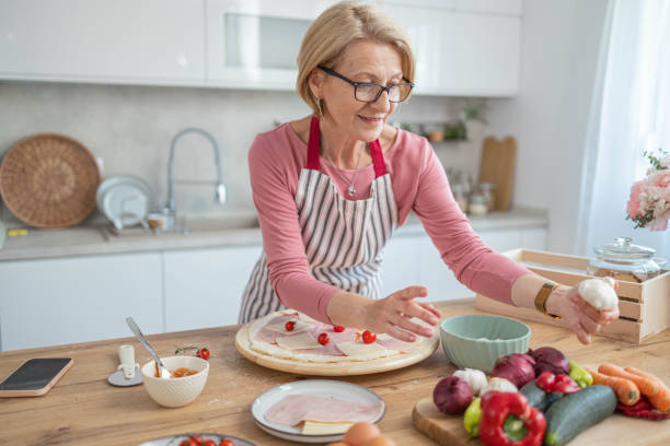 istock Senior woman in the kitchen is making pizza dough and mixing ingredients 1490280409