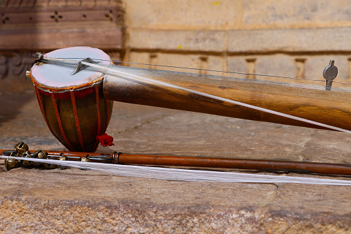 Stock photo showing close-up view of a ravanahatha an Indian folk bowed, stringed instrument left on a wall.