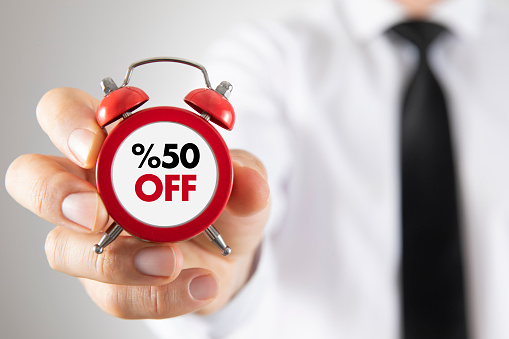 Businessman is holding a red clock with %50 off message