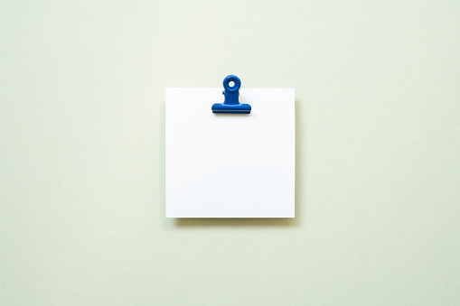 White blank memo pad with clip on mint background. top view, copy space