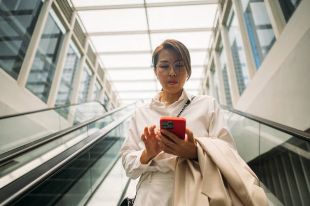 istock Asian Woman With a Smartphone Riding on an Escalator 1490288815