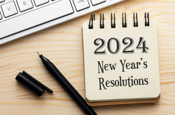 istock 2024 New Year's Resolutions text in a notebook on a wooden desk. 1490290564