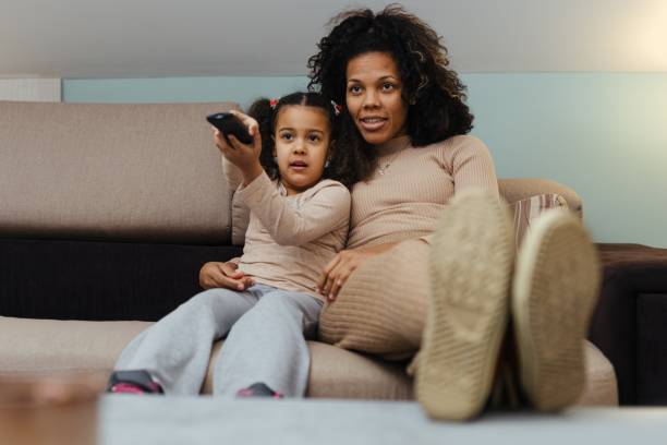 istock Smiling African Mother And Daughter Having Fun While Watching Television At Home 1490291511