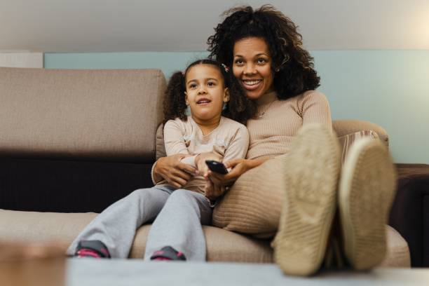 istock Smiling African Mother And Daughter Having Fun While Watching Television At Home 1490291532