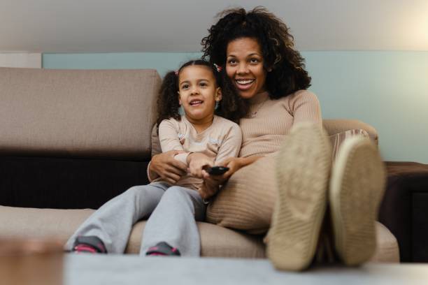 istock Smiling African Mother And Daughter Having Fun While Watching Television At Home 1490291539