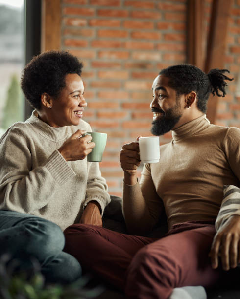 Happy black couple talking during tea time at home.