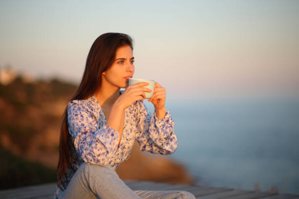 istock Woman drinking coffee at sunset on the beach 1490293222