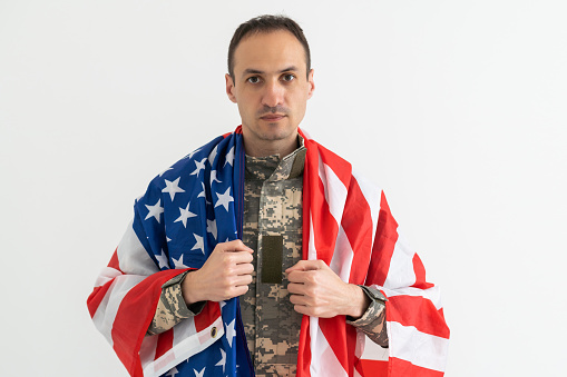 american military soldier holding flag. male officer in camouflage uniform. Concept of military, army