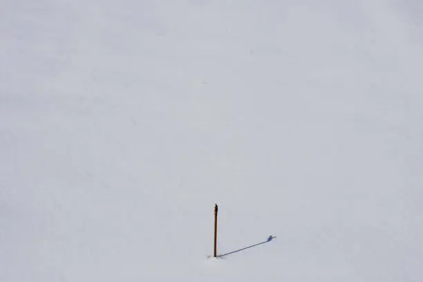 Photo of A close up on a small fire hydrant or brown metal pipe standing in the middle of a vast field covered fully with fresh snow and ice spotted on a Polish countryside on a sunny winter day