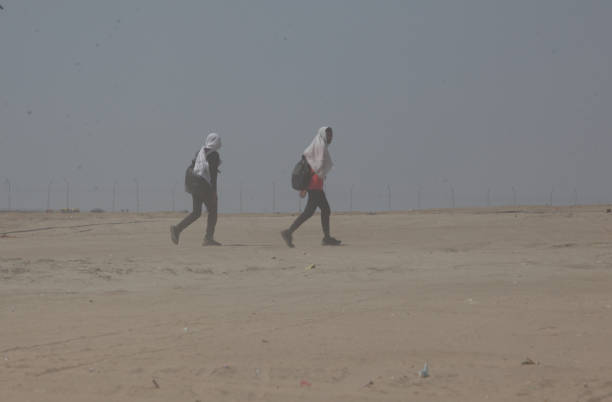 People walks during the heatwave conditions  at the bank of river  Gnages in Prayagraj, India.