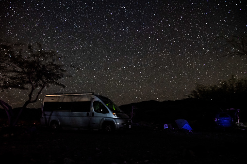 A camper van sits peacefully under a star filled sky in Death Valley National Park, California.
