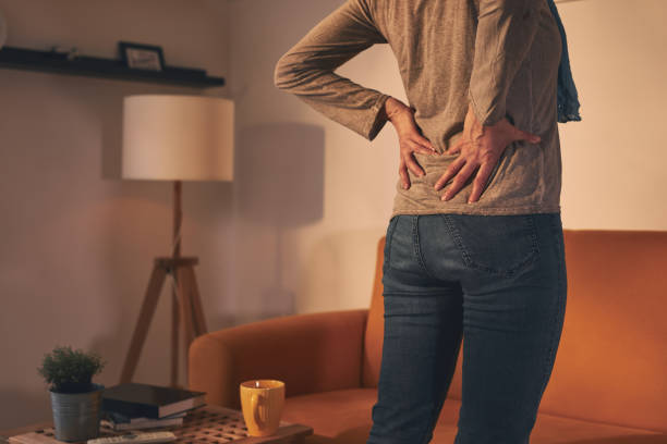 Woman with hip and back pain at home. stock photo