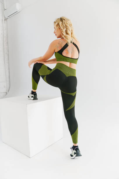 istock a blonde in a tracksuit makes stretching lunges on a white cube 1490304470