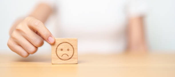 感情ブロックから不幸な怒った顔を選ぶ手。カスタマーレビュー, 悪い経験, 負帰還, 満足度, 調査, 評価サービス, 評価, 気分, 世界メンタルヘルスデーのコンセプト - 悪い ストックフォトと画像