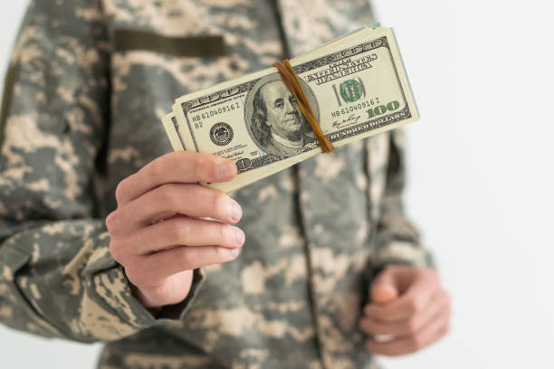 istock Army soldier holding money against white background 1490305095