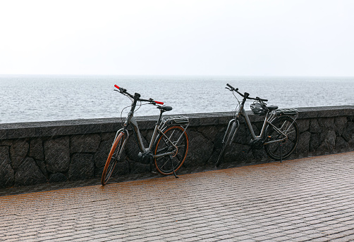 Electric bicycles in the rain . Two bicycles on the sea coast