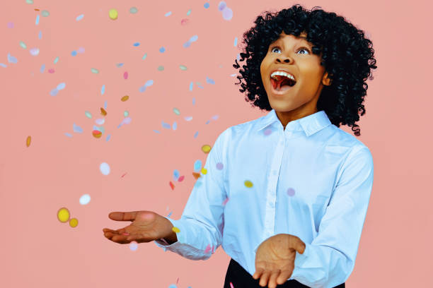 retrato de una mujer feliz con los brazos abiertos, sonriendo al confeti que cae - businesswoman black african descent studio shot fotografías e imágenes de stock